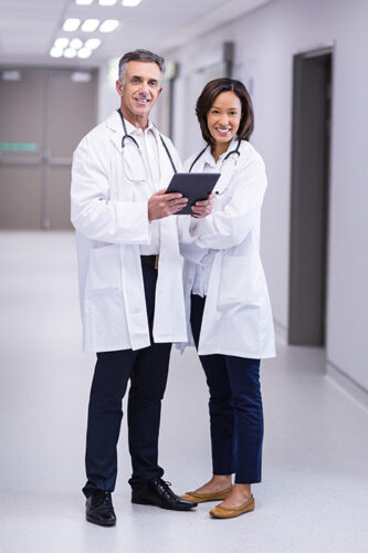 portrait-doctors-using-digital-tablet-corridor